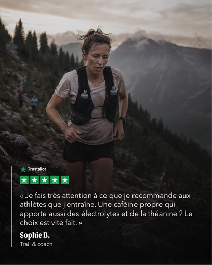 A woman trail running through a mountain landscape, wearing a light gray athletic shirt, black shorts, and a black hydration backpack. A quote overlay from Trustpilot is displayed on the left side against a dark mountain background.